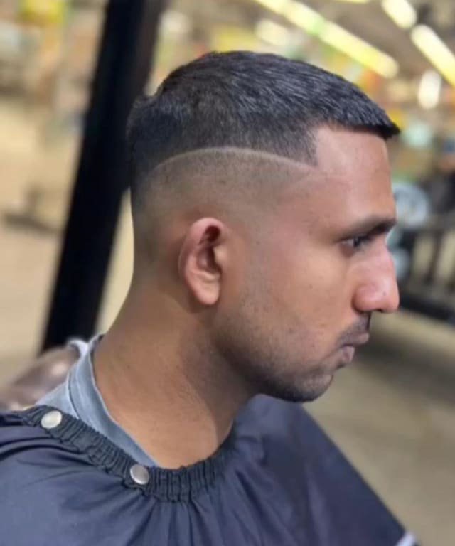 Skin fade with a shaved side part, viewed in profile