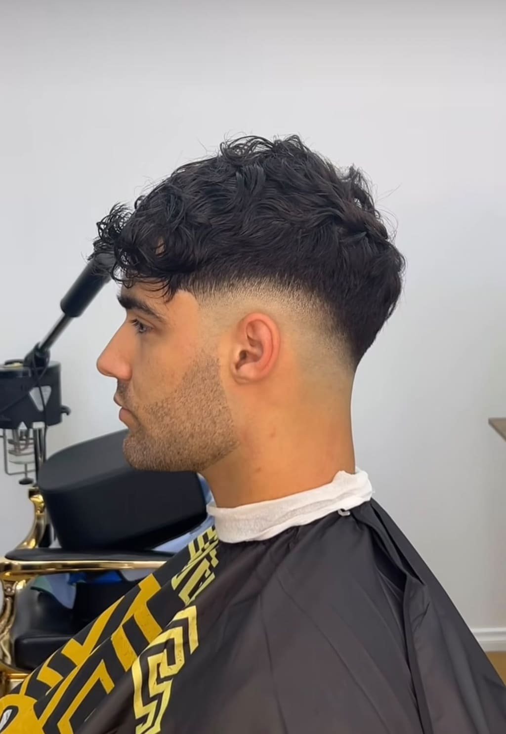 Textured curly top with a low drop fade, viewed in profile