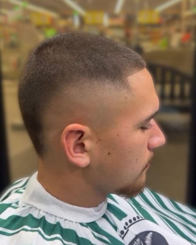 Short buzz cut with a tidy taper, viewed in profile