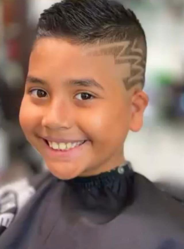 Smiling young client with a shaved pattern and fade