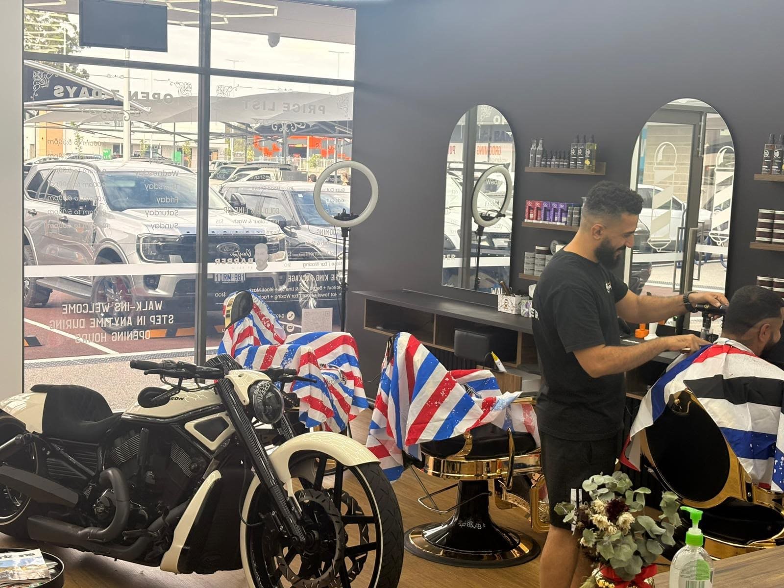 Shop floor with barber capes, mirrors and the motorcycle on display